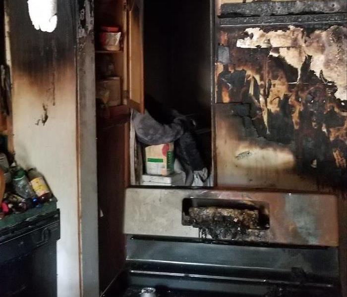 A photo of a stove and kitchen that have been through a fire